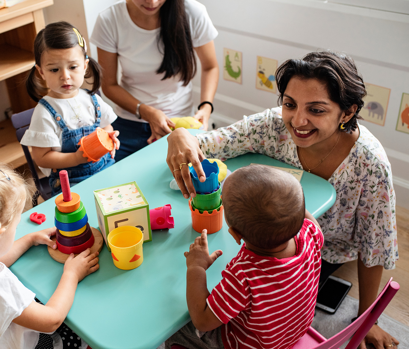 Nursery children playing with teacher in the classroom